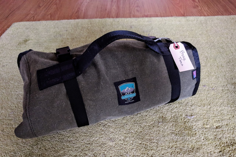 Rolled with some buckle straps and a nice handle. No rattles and easy to carry!